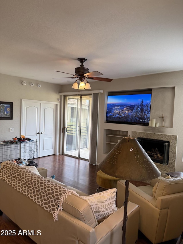 living room featuring ceiling fan, dark wood-type flooring, a textured ceiling, and a fireplace