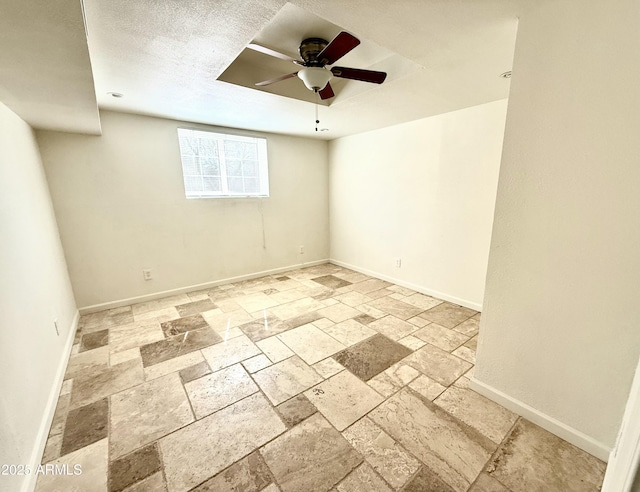 unfurnished room with stone tile floors, baseboards, and ceiling fan