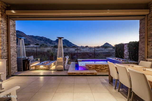 12311 E Black Rock Rd, Scottsdale, AZ 85255 - patio terrace at dusk featuring an outdoor fire pit, a mountain view, a patio area, and a fenced backyard