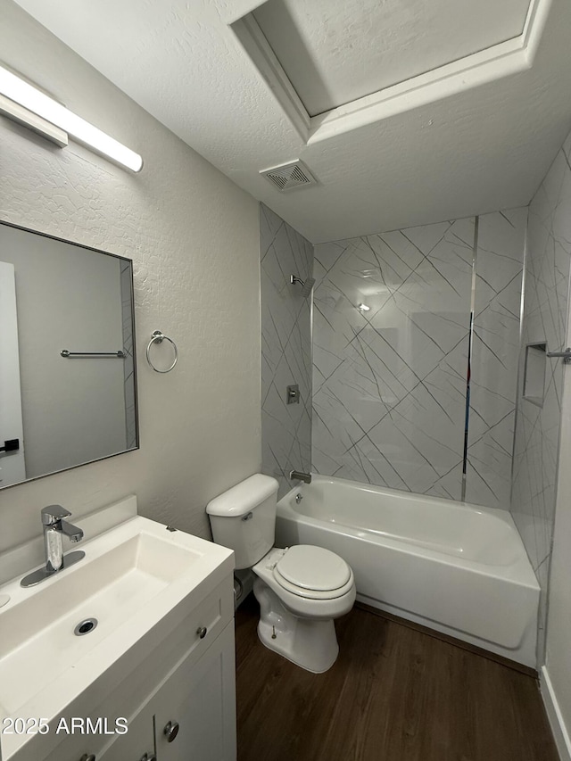 full bathroom with hardwood / wood-style floors, vanity, a textured ceiling, toilet, and tiled shower / bath