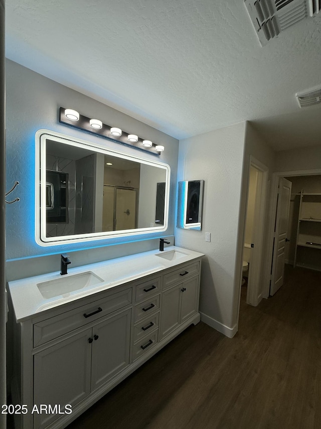 bathroom featuring hardwood / wood-style flooring, vanity, a textured ceiling, toilet, and walk in shower