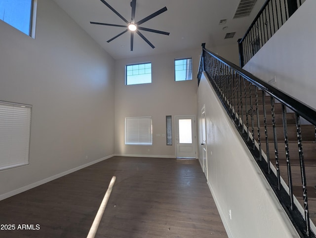 unfurnished living room featuring ceiling fan, a towering ceiling, and dark hardwood / wood-style flooring