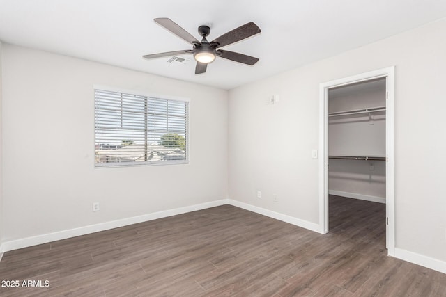 unfurnished bedroom with dark hardwood / wood-style flooring, a spacious closet, ceiling fan, and a closet