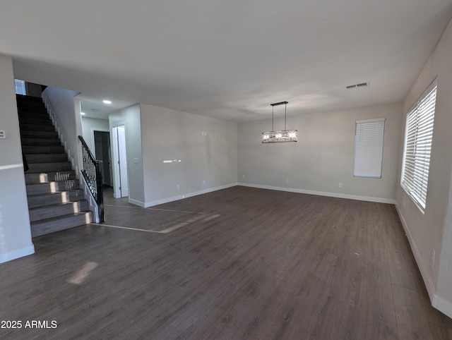 unfurnished room with dark wood-type flooring and a chandelier