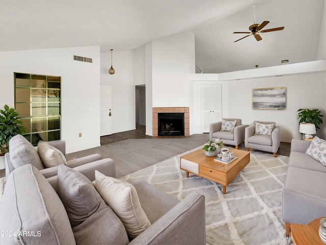 living room with ceiling fan, high vaulted ceiling, light wood-type flooring, and a tile fireplace