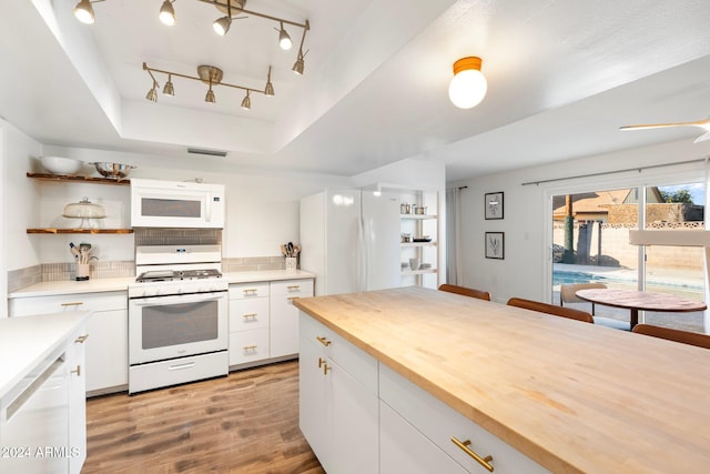 kitchen with white cabinetry, a raised ceiling, butcher block countertops, white appliances, and light wood-type flooring