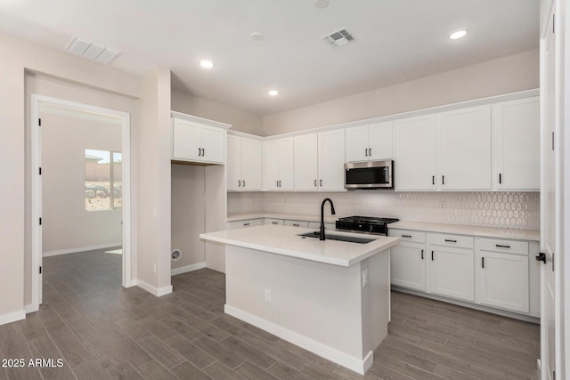 5664 N 205th Ln, Buckeye, AZ 85396 - kitchen with stainless steel microwave, a sink, tasteful backsplash, wood finished floors, and white cabinets