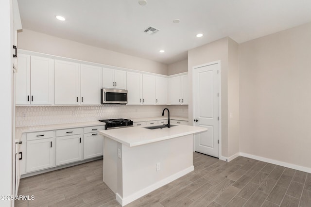 5664 N 205th Ln, Buckeye, AZ 85396 - kitchen featuring stainless steel microwave, a sink, range, tasteful backsplash, and light wood-style floors