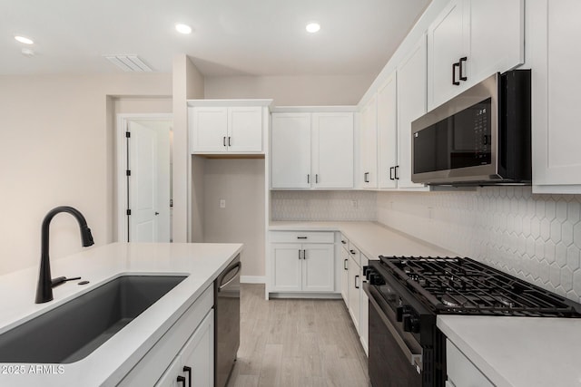 5664 N 205th Ln, Buckeye, AZ 85396 - kitchen with stainless steel appliances, a sink, light wood-style floors, white cabinets, and recessed lighting