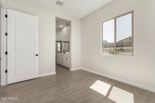 5664 N 205th Ln, Buckeye, AZ 85396 - unfurnished bedroom featuring light wood-style flooring, baseboards, and ensuite bath