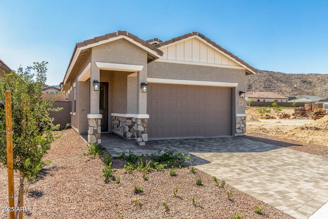 5664 N 205th Ln, Buckeye, AZ 85396 - view of front of property featuring stone siding, an attached garage, decorative driveway, a tile roof, and stucco siding