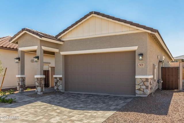 5664 N 205th Ln, Buckeye, AZ 85396 - view of front of house with a tiled roof, stone siding, decorative driveway, a garage, and stucco siding