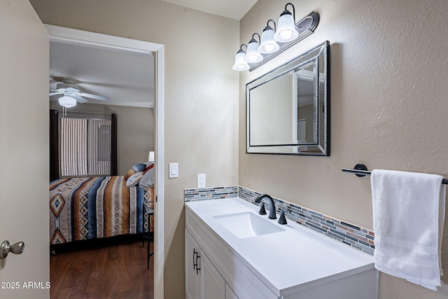 bathroom featuring ceiling fan, backsplash, hardwood / wood-style floors, vanity, and a textured ceiling