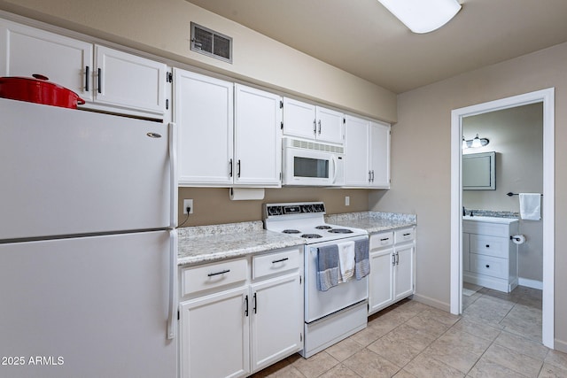 kitchen with white cabinetry, light stone countertops, and white appliances