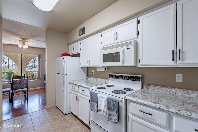 kitchen featuring light tile patterned flooring, white appliances, light stone countertops, and white cabinets