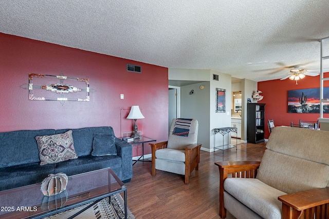 living room featuring ceiling fan, wood-type flooring, and a textured ceiling