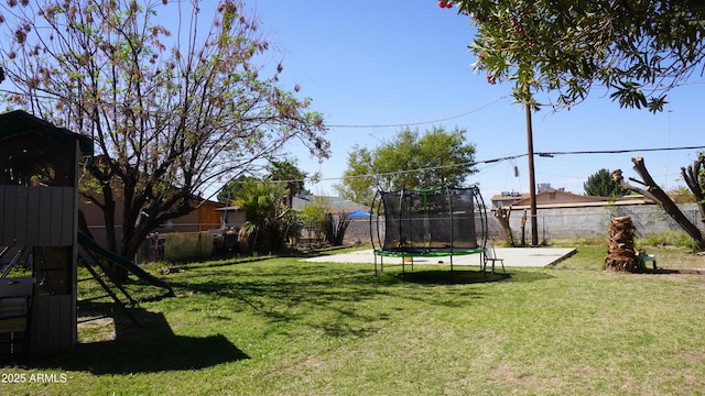 view of yard featuring a trampoline, a fenced backyard, and a playground