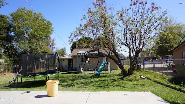 view of yard featuring a playground, a trampoline, and a fenced backyard