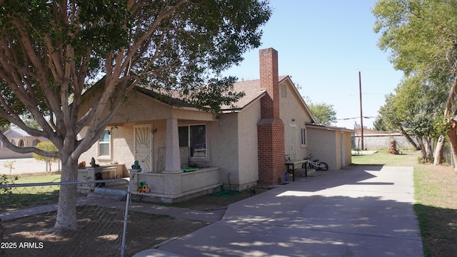 exterior space featuring stucco siding, a chimney, and fence