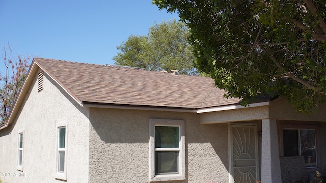 view of side of property with stucco siding and roof with shingles