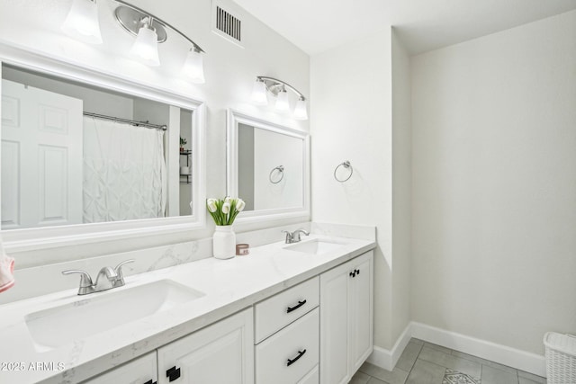 bathroom featuring double vanity, tile patterned flooring, visible vents, and a sink