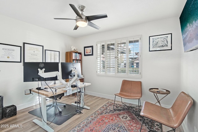 office space with light wood-type flooring, ceiling fan, and baseboards