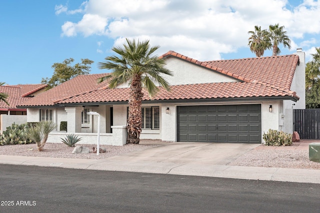 mediterranean / spanish house with a garage, a tile roof, concrete driveway, stucco siding, and a chimney