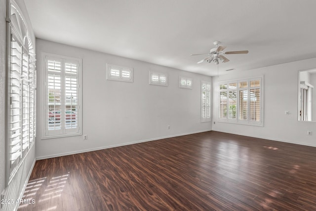 spare room featuring dark wood finished floors, a ceiling fan, and baseboards