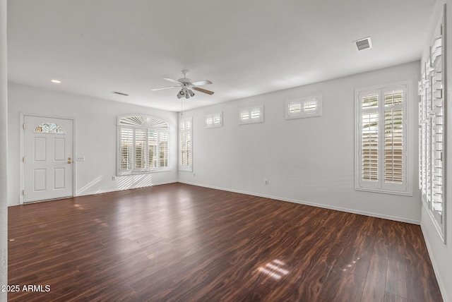 spare room featuring dark wood-style floors, a ceiling fan, and visible vents