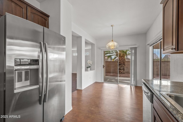 kitchen featuring dark wood-type flooring, pendant lighting, dark countertops, stainless steel appliances, and baseboards