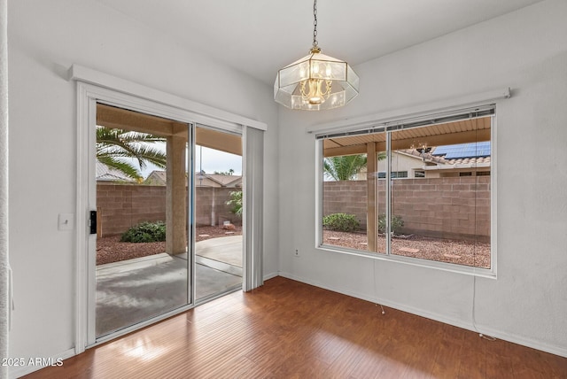 unfurnished room with wood finished floors, baseboards, and a chandelier