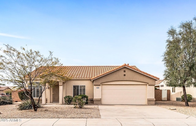 mediterranean / spanish-style house with fence, a tiled roof, concrete driveway, stucco siding, and a garage