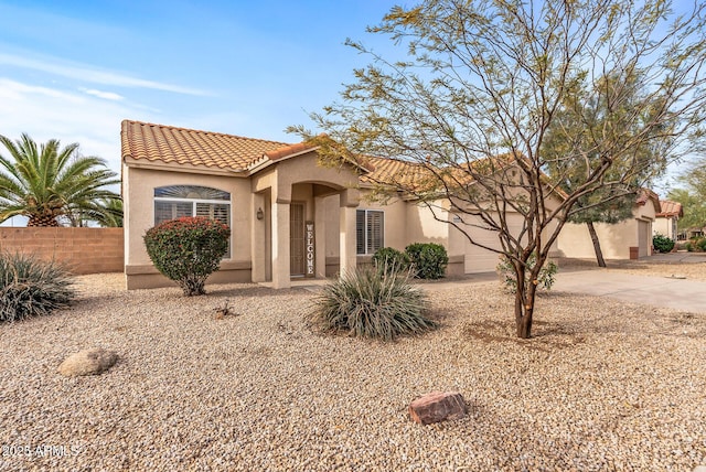 mediterranean / spanish house with stucco siding, a tile roof, and fence