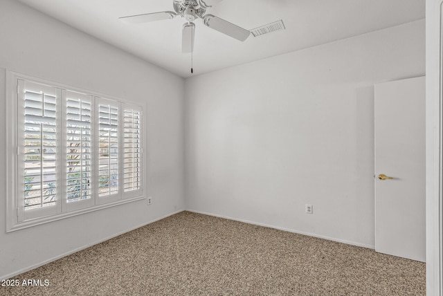 carpeted spare room with visible vents and a ceiling fan