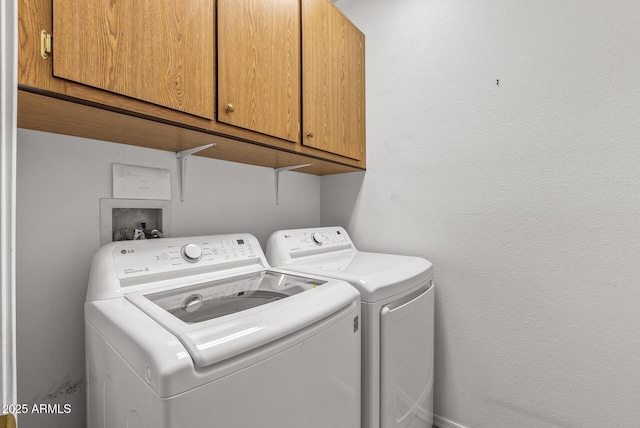 laundry area with cabinet space, washing machine and dryer, and a textured wall