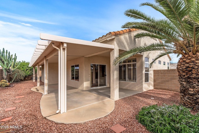 back of property with a tiled roof, a patio area, fence, and stucco siding