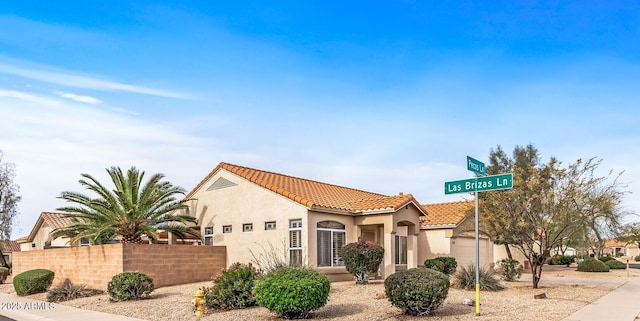 mediterranean / spanish house featuring fence, driveway, stucco siding, a garage, and a tiled roof