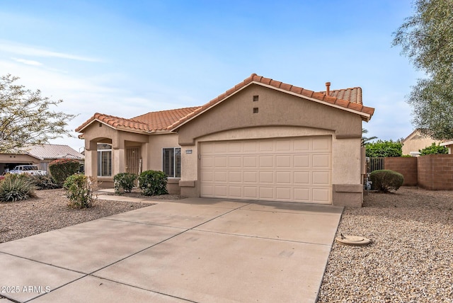 mediterranean / spanish home featuring stucco siding, a tile roof, fence, concrete driveway, and a garage