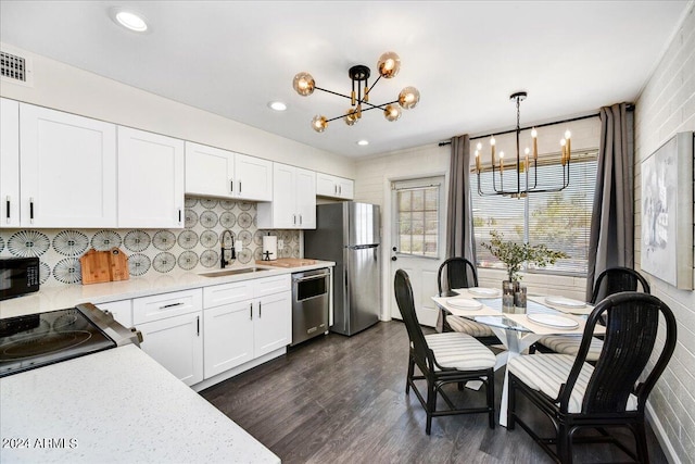 kitchen with an inviting chandelier, decorative light fixtures, stainless steel appliances, sink, and dark wood-type flooring