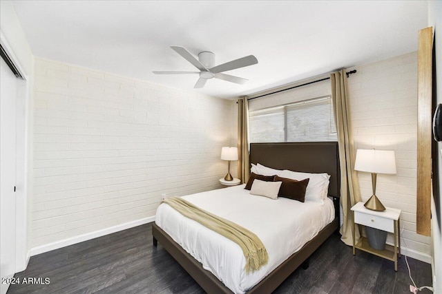 bedroom featuring dark wood-type flooring, ceiling fan, and brick wall