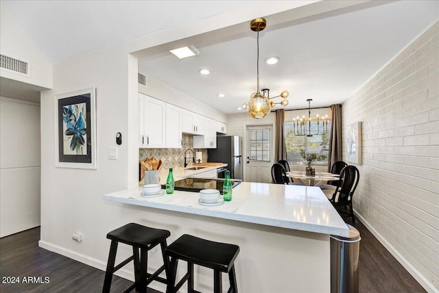 kitchen with light stone counters, dark hardwood / wood-style flooring, sink, kitchen peninsula, and pendant lighting