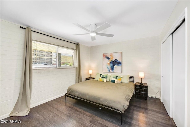 bedroom featuring dark hardwood / wood-style flooring, brick wall, ceiling fan, and a closet