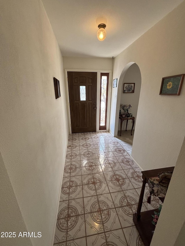 foyer with arched walkways and light tile patterned flooring