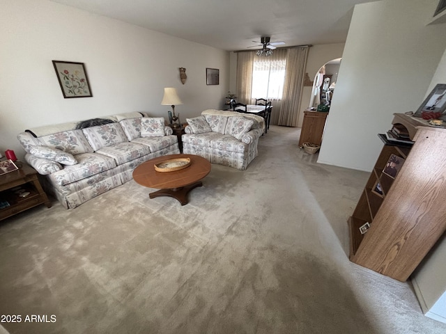 living area featuring arched walkways, light carpet, and ceiling fan