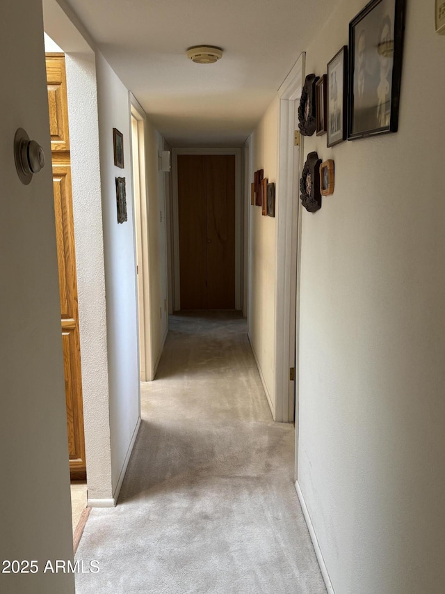 hall with baseboards and light colored carpet