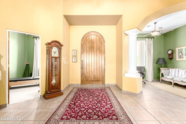 tiled foyer with a ceiling fan, arched walkways, ornate columns, and baseboards