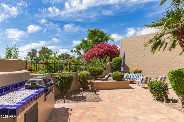 view of patio with fence, an outdoor hangout area, and an outdoor kitchen