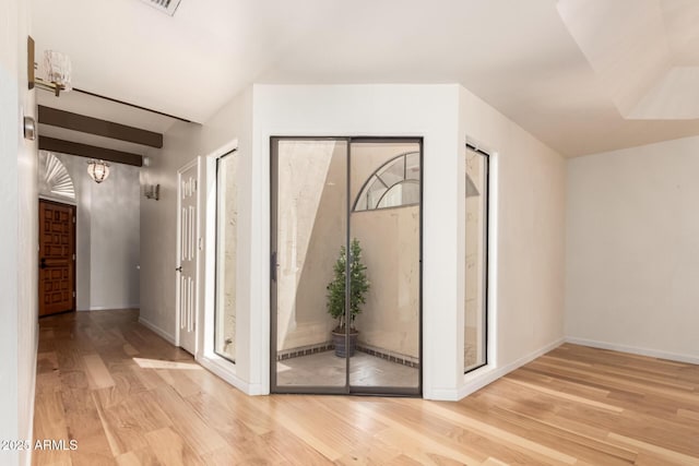 hall featuring baseboards, wood finished floors, and a chandelier