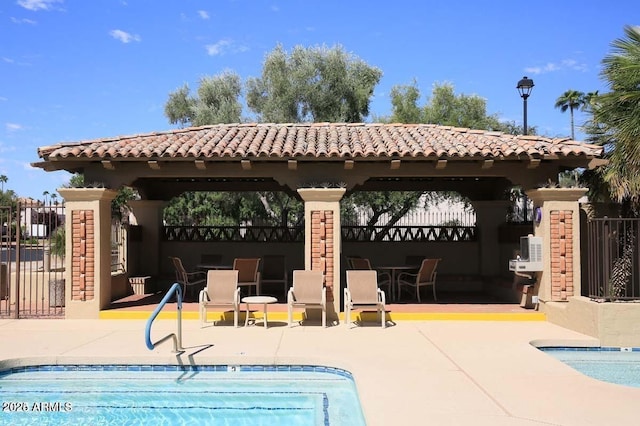 back of house featuring a gazebo, fence, a tile roof, and stucco siding