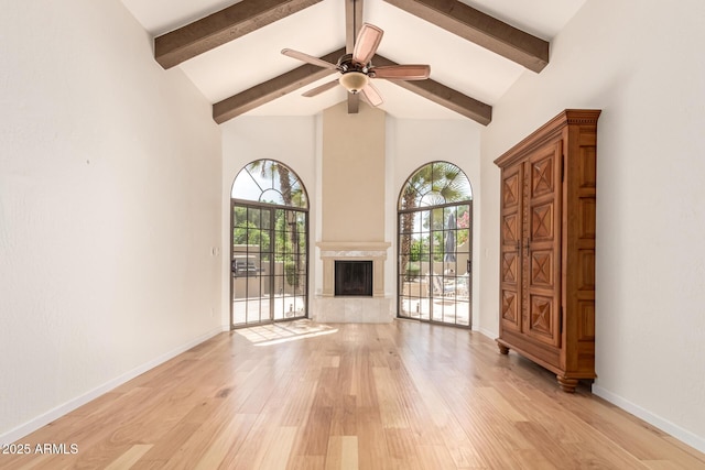 unfurnished living room featuring high vaulted ceiling, a ceiling fan, light wood finished floors, and beam ceiling